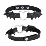 Winged Heart Choker — A black faux-leather choker band with a small heart pendant framed by a pair of bat wings.